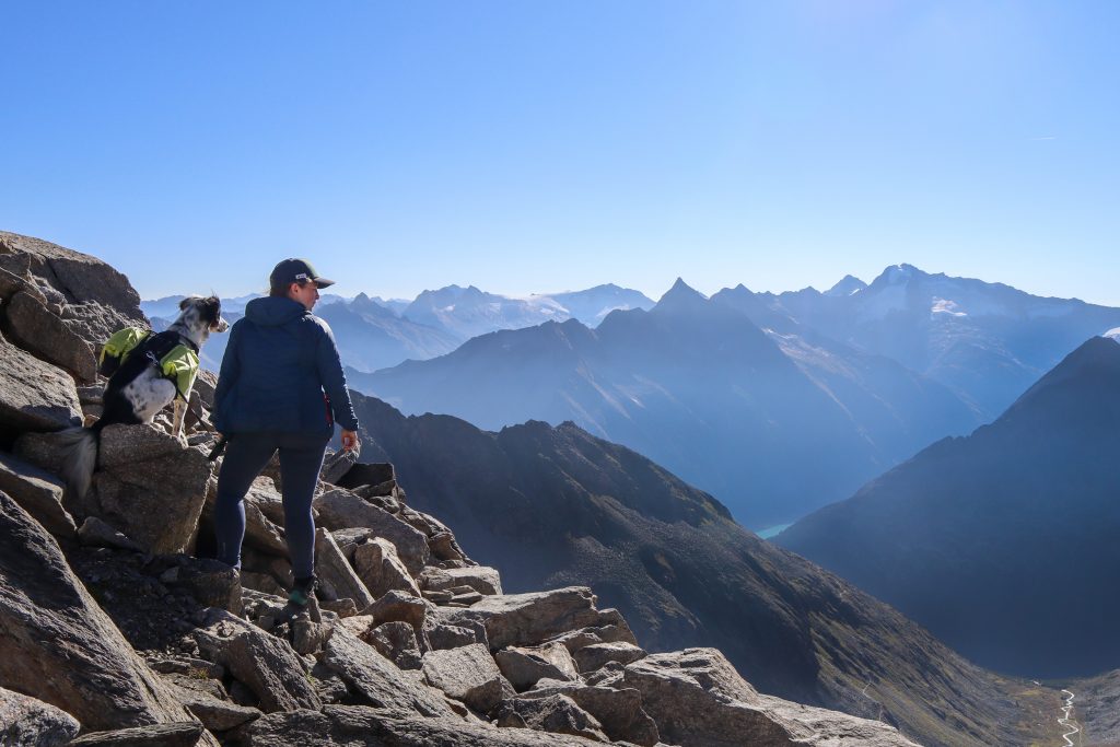 Wanderin mit Hund auf dem felsigen Steig an der Alpeiner Scharte oberhalb des Pfitscher Jochs